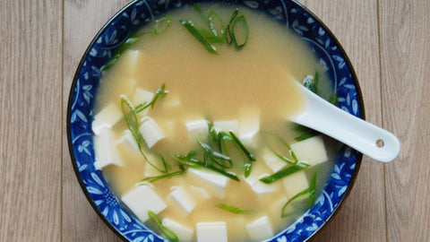 a bowl of miso soup with cubed pieces of silky soft tofu